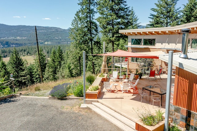 view of play area featuring a forest view, a mountain view, and a patio