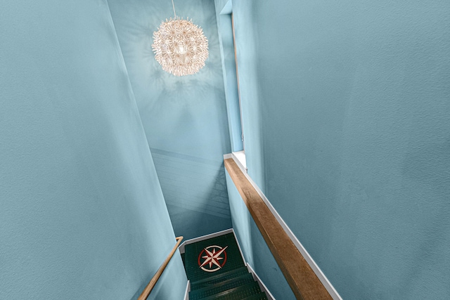 stairs featuring an inviting chandelier, carpet flooring, and baseboards