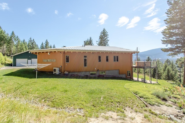 back of property with a garage, a lawn, an outbuilding, and metal roof