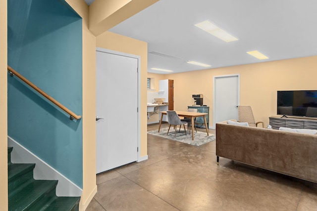 living area featuring stairway, baseboards, and finished concrete floors