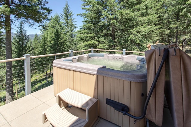 wooden terrace featuring a hot tub and a wooded view