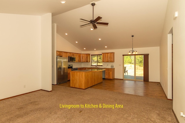 kitchen with high vaulted ceiling, hanging light fixtures, appliances with stainless steel finishes, carpet flooring, and a kitchen island