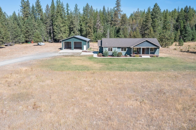 single story home with a garage, an outbuilding, a front yard, and covered porch