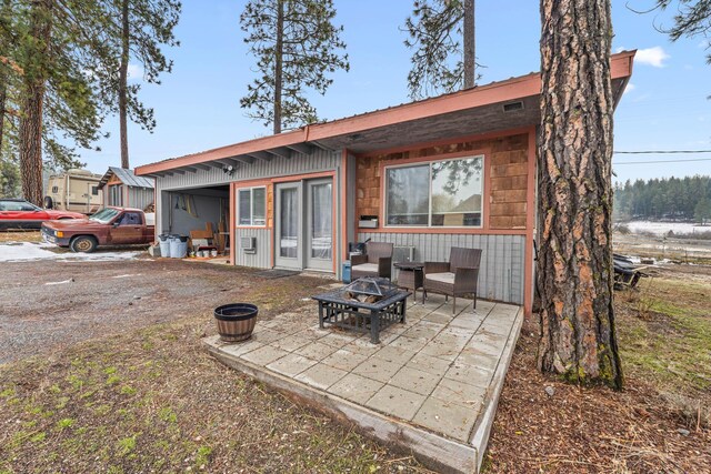 rear view of property featuring a fire pit and a patio