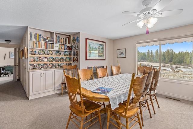 carpeted dining area with ceiling fan