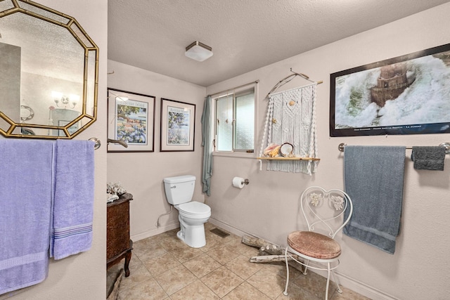 bathroom featuring toilet, tile patterned floors, and a textured ceiling