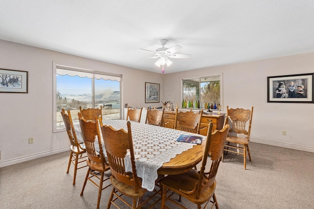 dining space with ceiling fan and light carpet