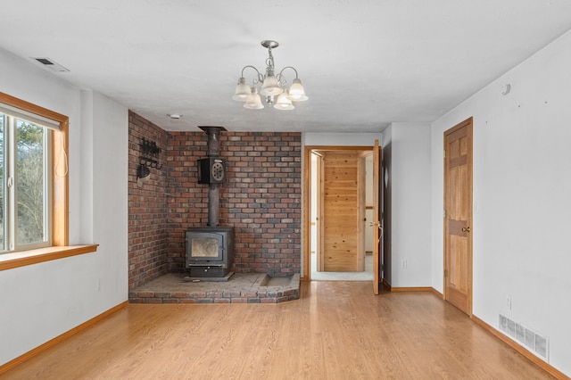 2829 Cottonwood Creek Rd, Chewelah, WA 99109 - unfurnished living room with wood finished floors, a wood stove, a chandelier, and baseboards