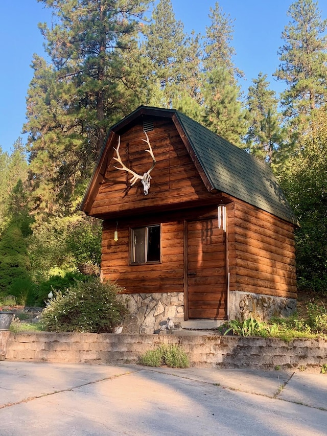 59 Bisbee Creek Ln, Kettle Falls, WA 99141 - view of property exterior with roof with shingles, stone siding, and an outbuilding