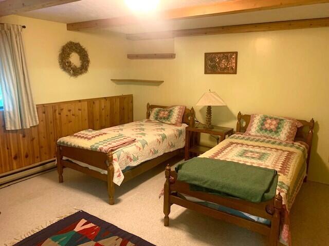 59 Bisbee Creek Ln, Kettle Falls, WA 99141 - carpeted bedroom featuring beamed ceiling, wainscoting, wood walls, and a baseboard radiator