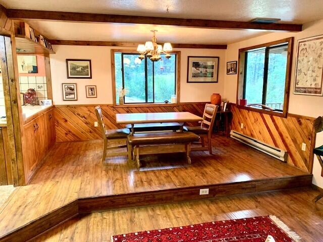 59 Bisbee Creek Ln, Kettle Falls, WA 99141 - dining room with a baseboard heating unit, beamed ceiling, a chandelier, wood finished floors, and wainscoting
