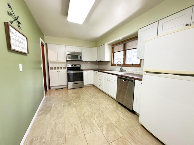 824 S Chester St, Colville, WA 99114 - kitchen featuring appliances with stainless steel finishes, a sink, decorative backsplash, dark countertops, and white cabinetry