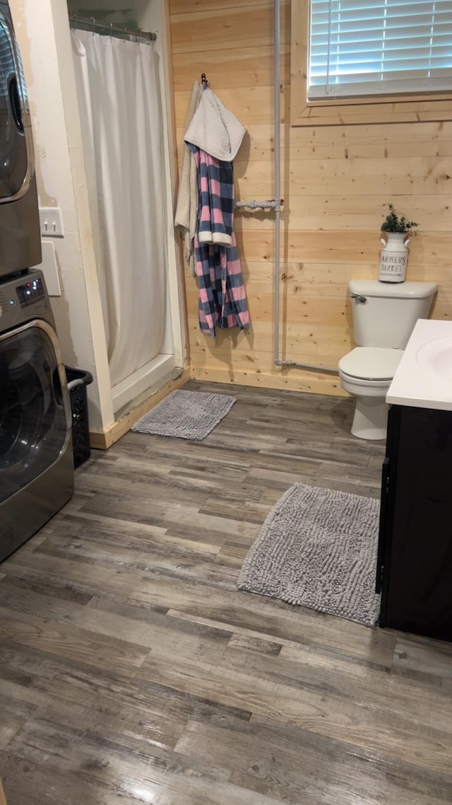 980 N Elm St, Colville, WA 99114 - bathroom featuring stacked washer / dryer, vanity, curtained shower, wood finished floors, and toilet