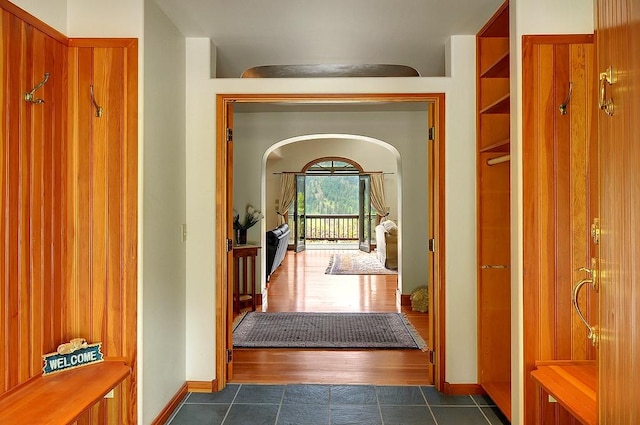 hall with dark tile patterned flooring and baseboards