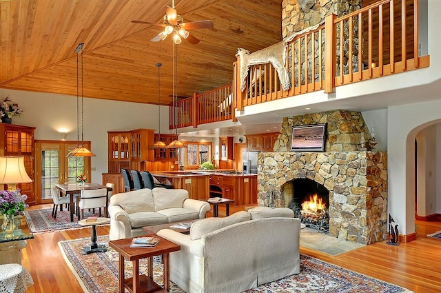 living area with arched walkways, high vaulted ceiling, a ceiling fan, and wood ceiling
