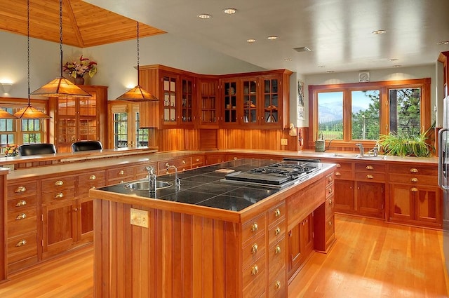 kitchen featuring light wood-style floors, a sink, brown cabinets, and a kitchen island