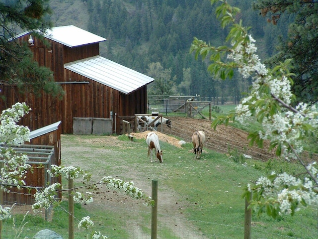 view of yard with a barn, a forest view, and an outbuilding