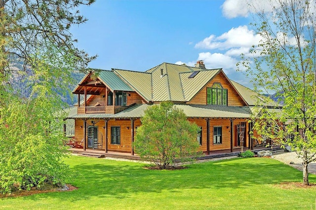 exterior space featuring a standing seam roof, a chimney, a lawn, and a porch