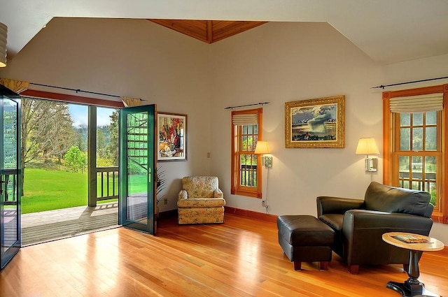 sitting room featuring high vaulted ceiling, baseboards, and light wood finished floors