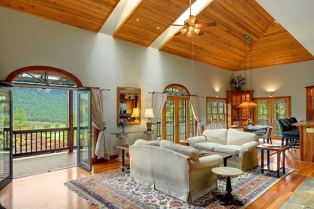 living area featuring wood finished floors, high vaulted ceiling, wood ceiling, french doors, and a ceiling fan