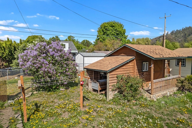 back of house featuring fence and a shingled roof