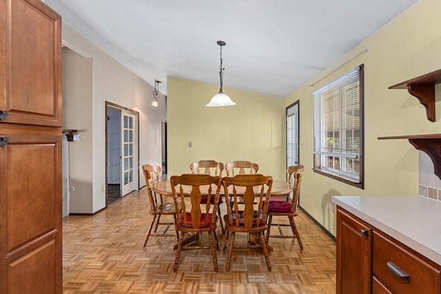 dining space featuring vaulted ceiling and baseboards