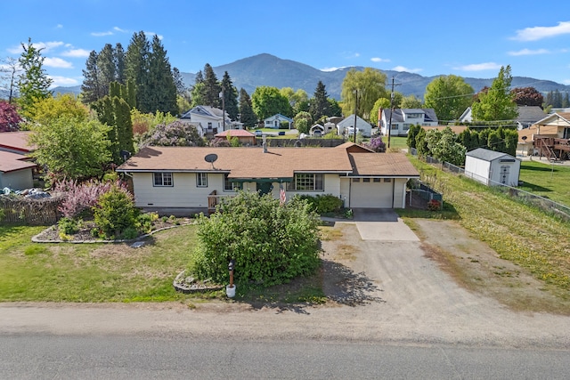 ranch-style home with a garage, concrete driveway, a mountain view, and a residential view