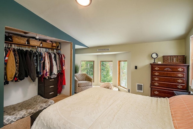 carpeted bedroom with heating unit, a closet, and lofted ceiling