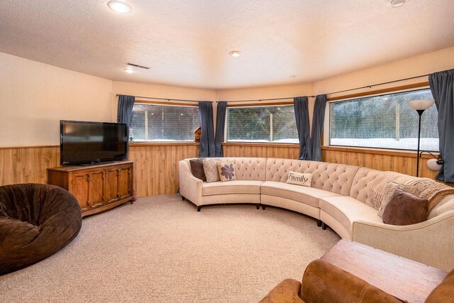 carpeted living room featuring a textured ceiling and wooden walls