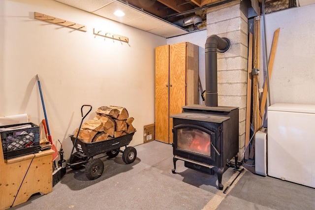 room details featuring a wood stove, refrigerator, and concrete flooring