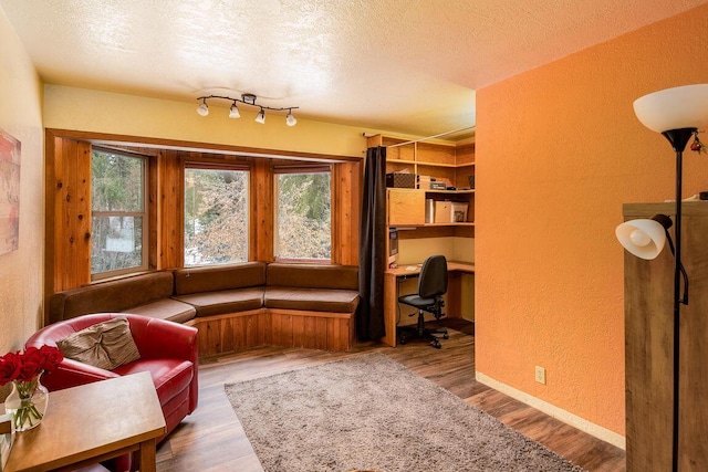 sitting room featuring hardwood / wood-style flooring, a textured ceiling, and built in desk