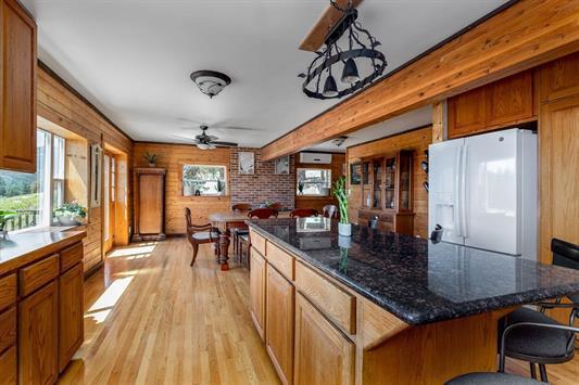 3439 Northport Flat Creek Rd Unit B, Kettle Falls, WA 99141 - kitchen with white refrigerator with ice dispenser, light wood finished floors, a ceiling fan, brown cabinetry, and a kitchen island