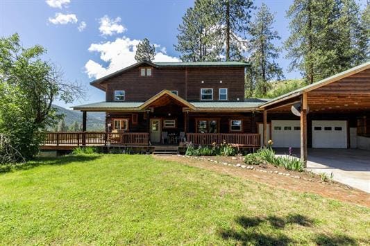 3439 Northport Flat Creek Rd Unit B, Kettle Falls, WA 99141 - back of house featuring a yard, a garage, driveway, covered porch, and an attached carport