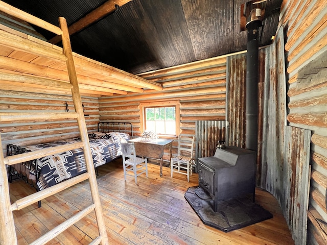 bedroom with hardwood / wood-style flooring, rustic walls, a wood stove, and wood ceiling