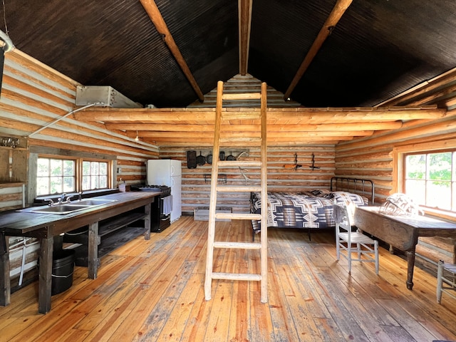 interior space featuring wood-type flooring, multiple windows, lofted ceiling with beams, and log walls