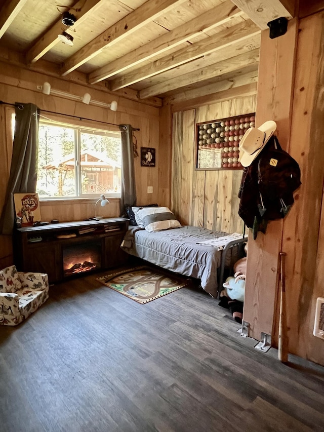 bedroom with wooden ceiling, wooden walls, beamed ceiling, and wood finished floors