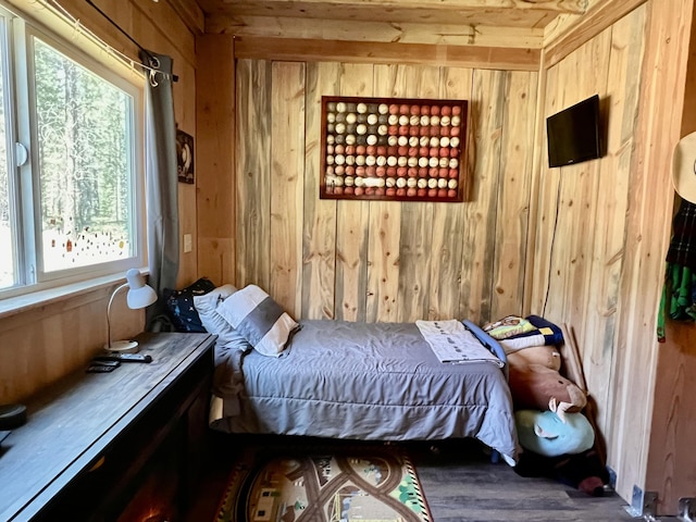 bedroom with multiple windows, wood walls, and wood finished floors