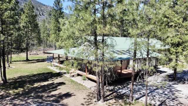 exterior space featuring a deck with mountain view, a forest view, and metal roof