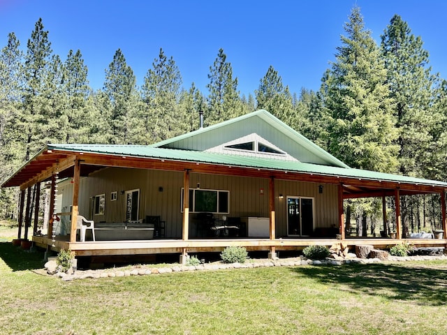 rear view of property with a yard, a deck, and metal roof