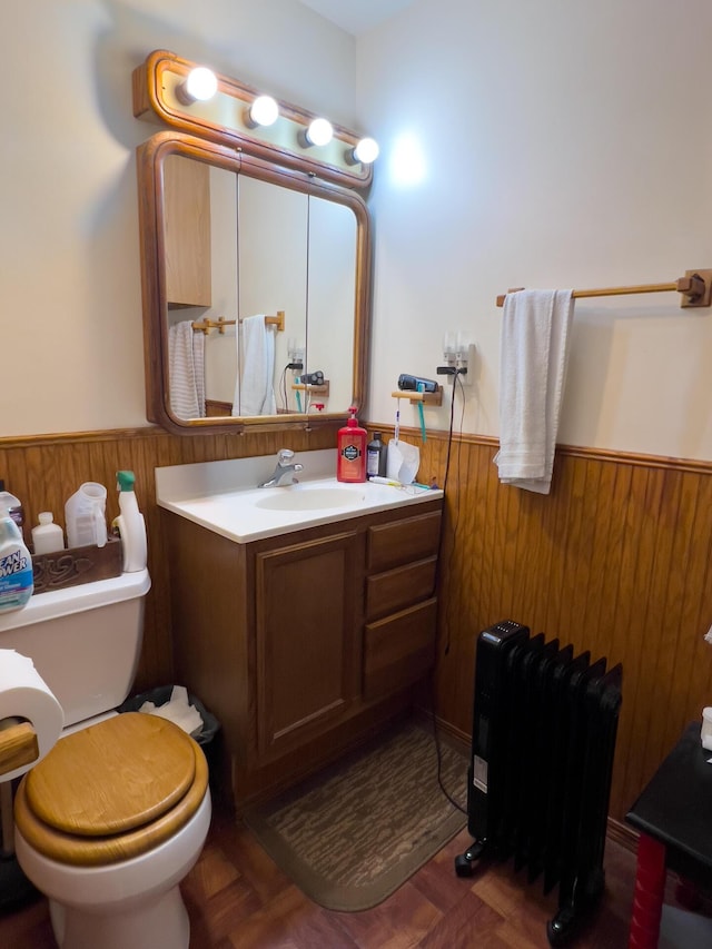 bathroom with radiator heating unit, toilet, vanity, and parquet floors