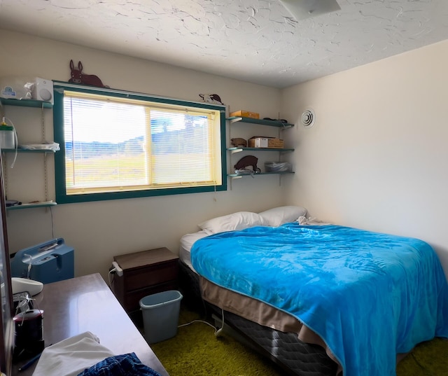 bedroom featuring a textured ceiling and dark carpet