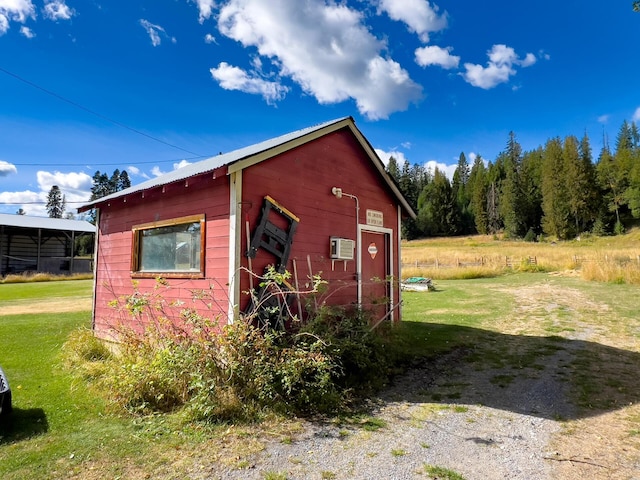 view of outbuilding featuring a wall mounted air conditioner and a lawn