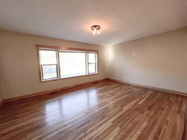 empty room with wood-type flooring and a textured ceiling