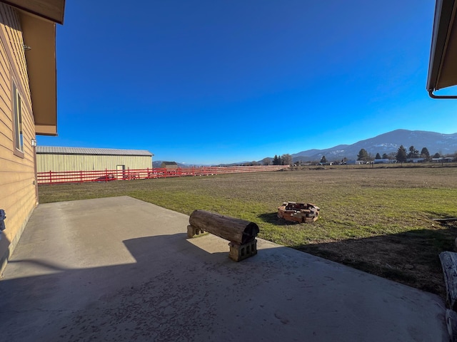 view of yard with an outdoor fire pit, a mountain view, and a rural view