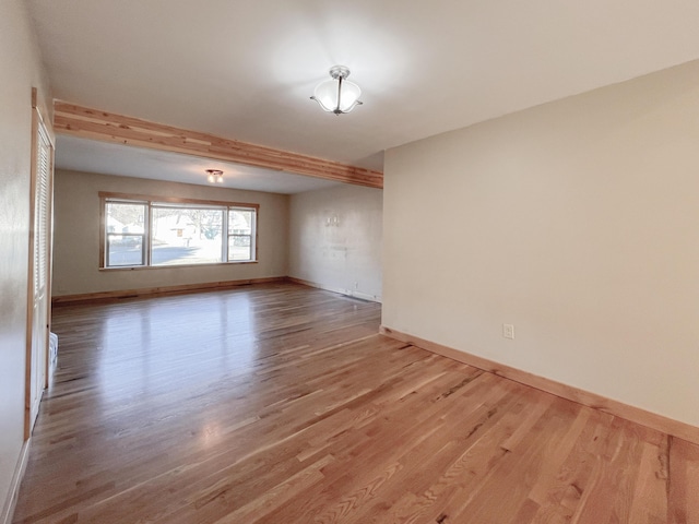 spare room featuring hardwood / wood-style flooring and beamed ceiling