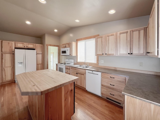 kitchen featuring light brown cabinetry, sink, a center island, vaulted ceiling, and white appliances