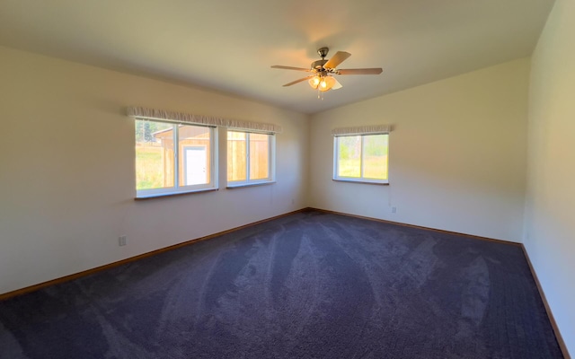 spare room with dark colored carpet, vaulted ceiling, baseboards, and ceiling fan