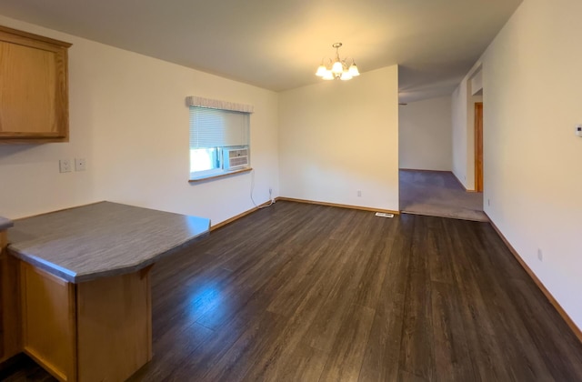 unfurnished dining area with a chandelier, cooling unit, dark wood finished floors, and baseboards