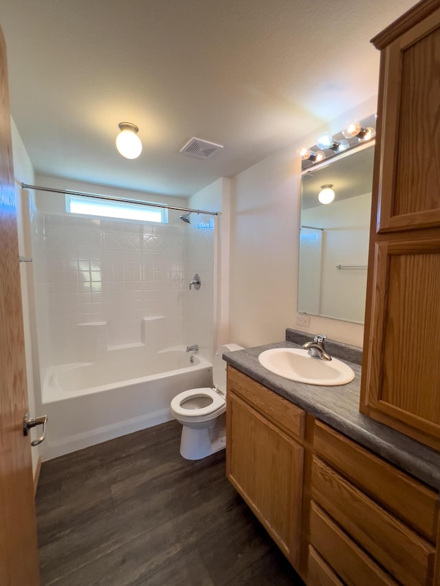 bathroom with toilet, wood finished floors, vanity, visible vents, and  shower combination