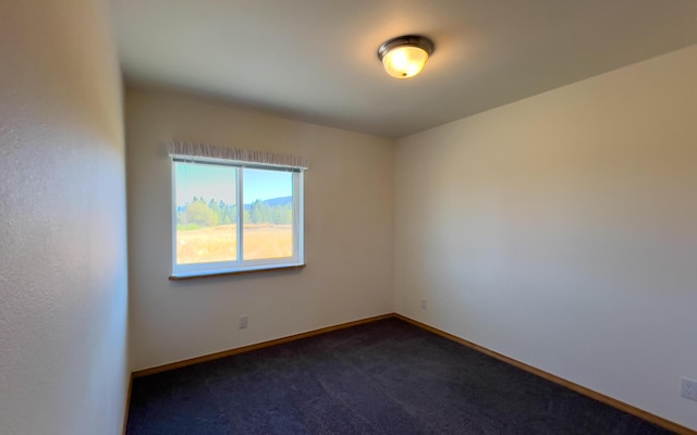 empty room with dark carpet and baseboards